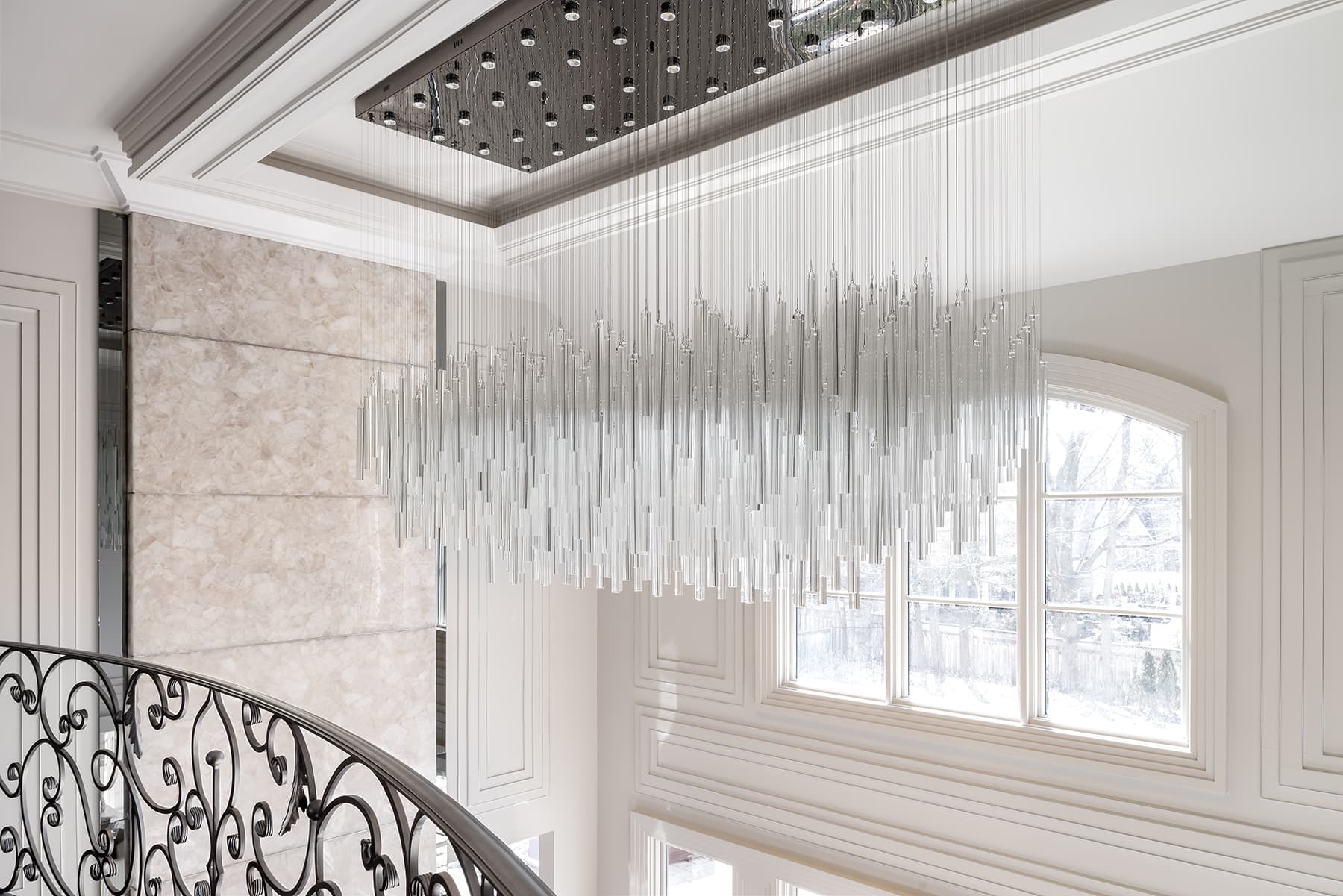 Two-storey foyer of Project 01 with a rain-cluster crystal chandelier gently drifting in still air.