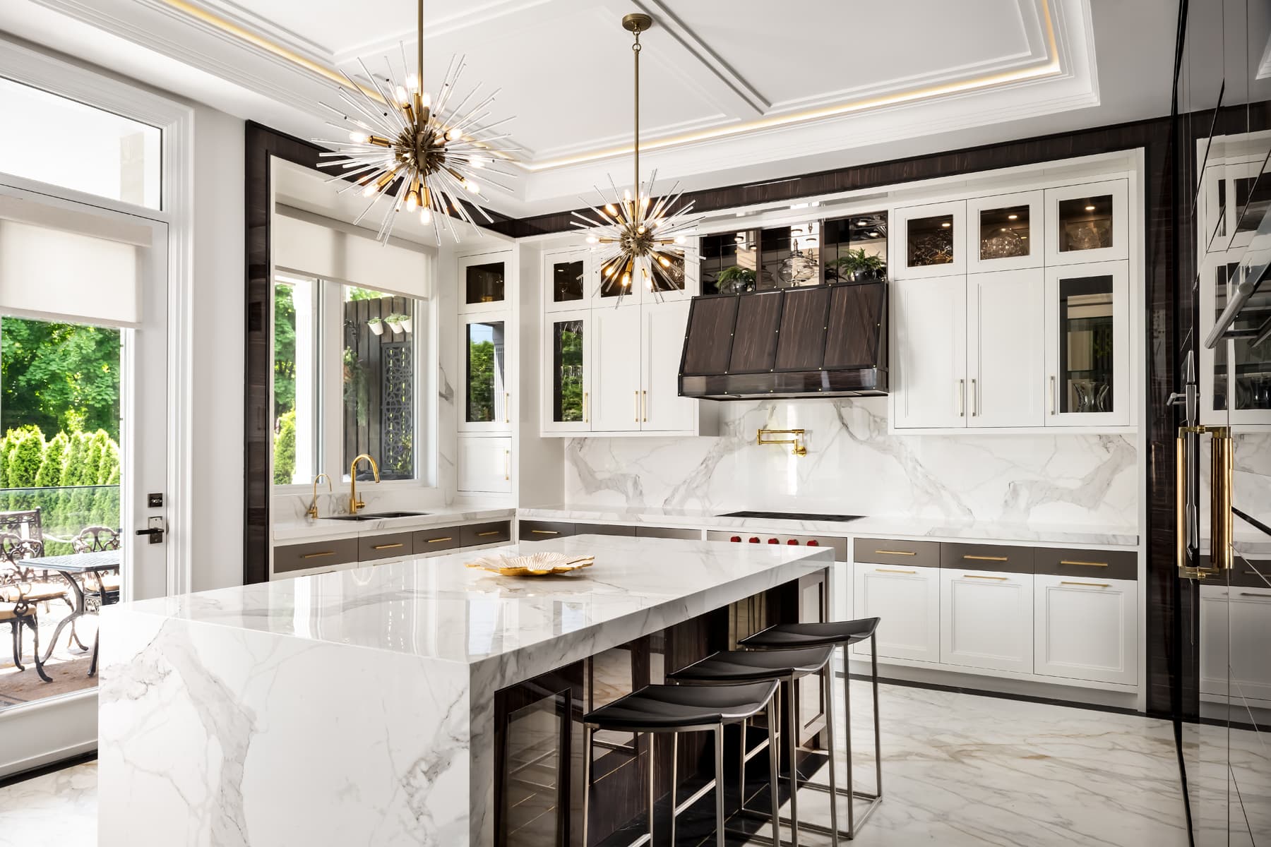Alternate kitchen angle showing the island, marble waterfall edge, and window over the sink.